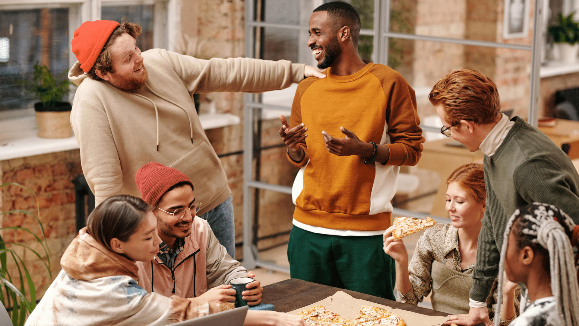 Friends laughing and having a good time over pizza outside.